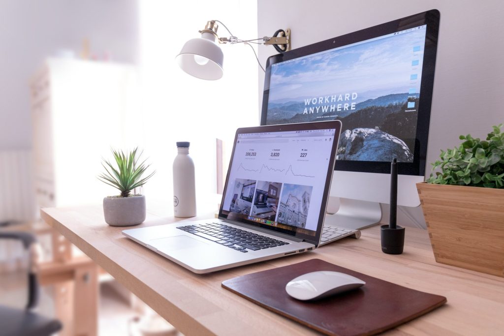 MacBook Pro auf dem Tisch neben einem weißen iMac und einer Magic Mouse